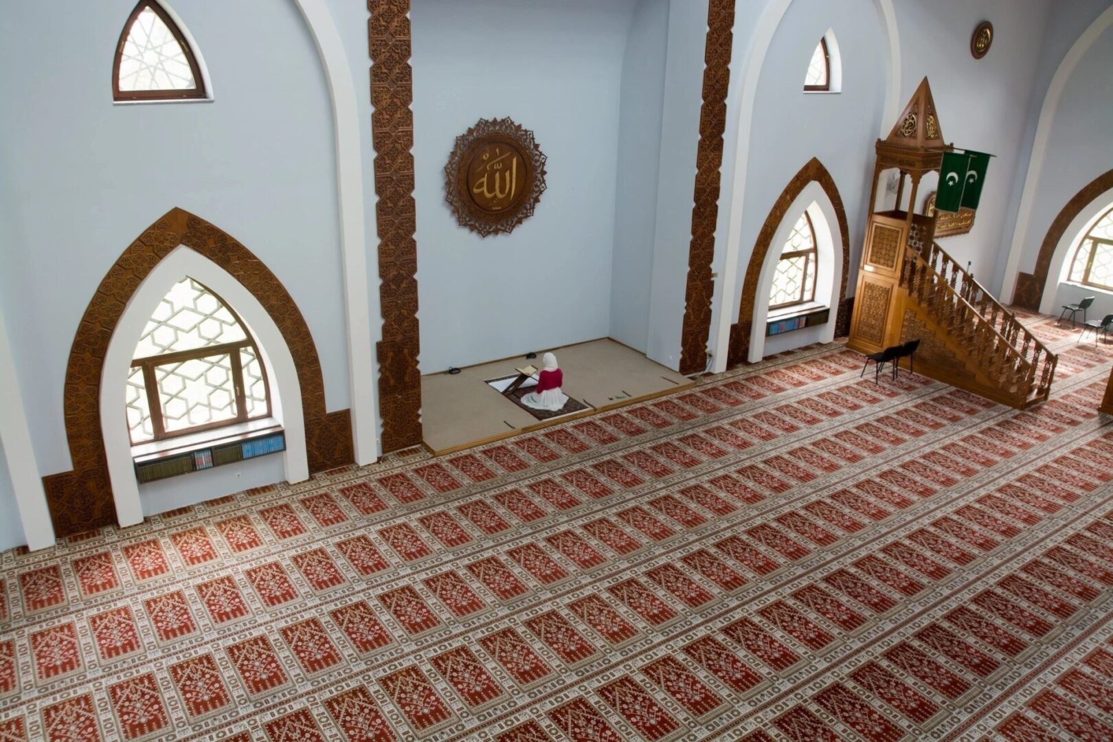 Inside a mosque with blue walls and brown floors and lots of lighting