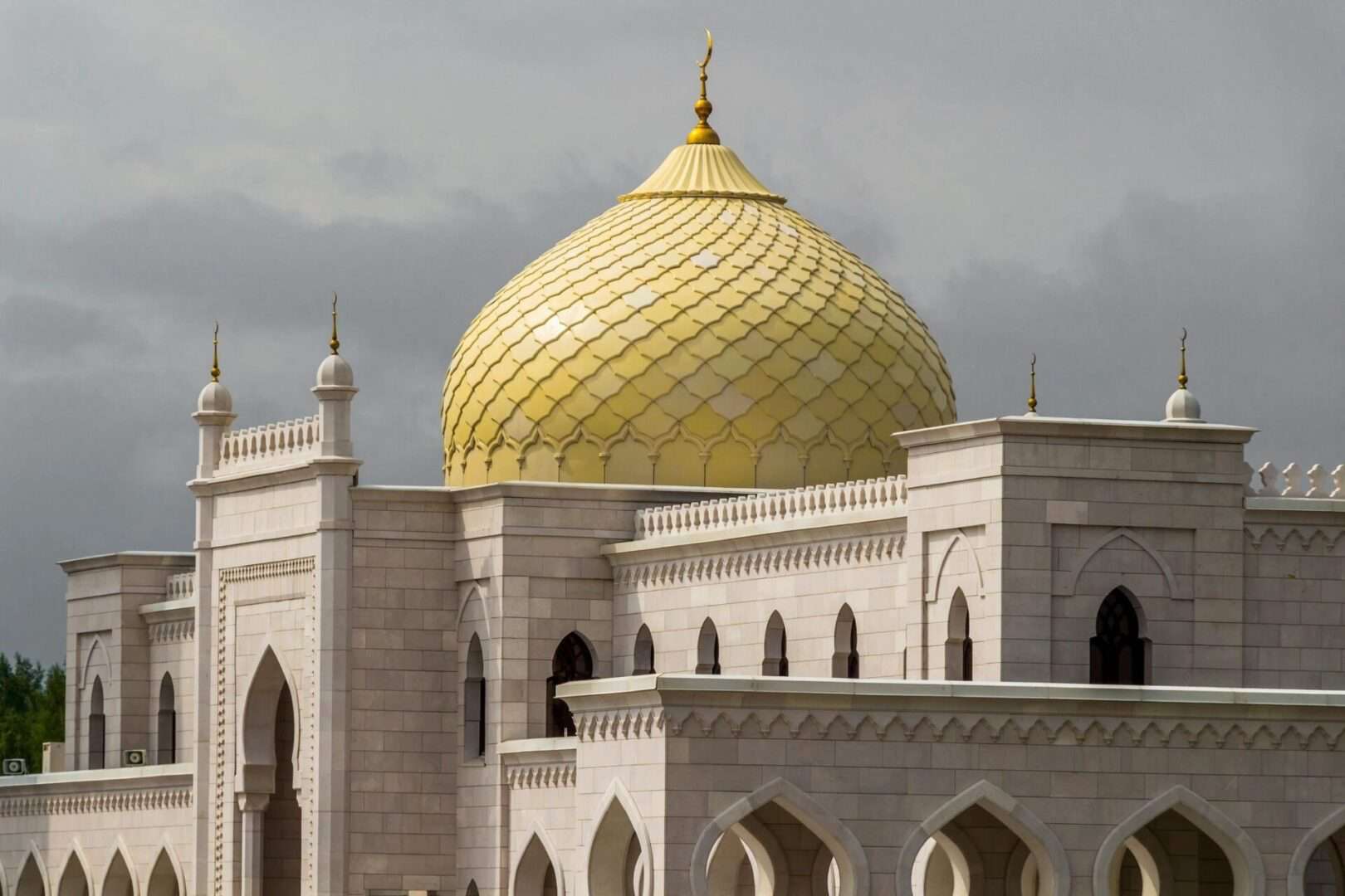 Gold dome mosque with white stone walls on a cloudy day